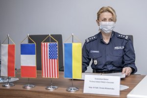 Komendant-Rektor WSPol siedzi przy stole, obok widoczne są ustawione na stole miniaturowe flagi krajów