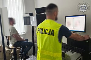 Na zdjęciu widoczny technik kryminalistyki, który robi zdjęcia sygnalityczne zatrzymanemu mężczyźnie.
